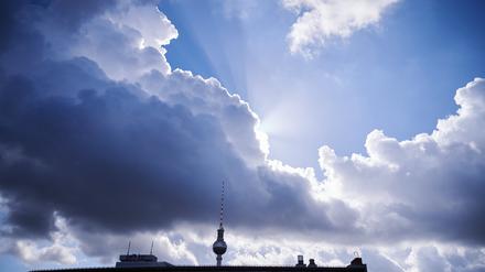 Die Sonnenstrahlen kommen hinter einer dunklen Wolke über dem Berliner Fernsehturm hervor. 