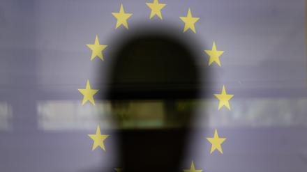 Eine Silhouette ist vor einer Projektion der EU-Flagge zu sehen (Symbolbild).